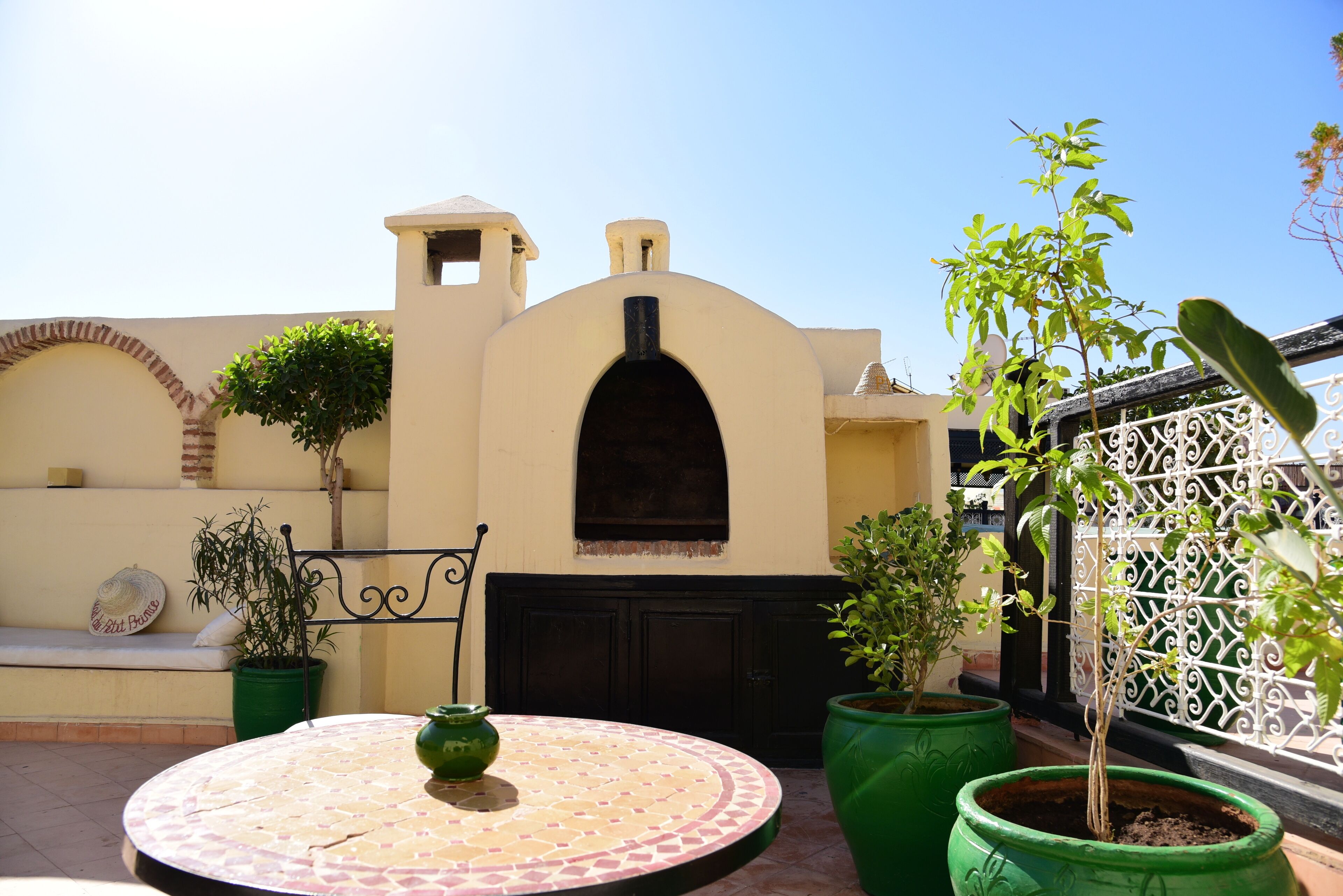 Un patio con una mesa redonda, plantas en macetas y un muro decorativo.