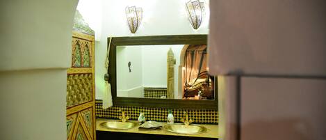Une salle de bain avec deux lavabos, un miroir et un mur décoratif.