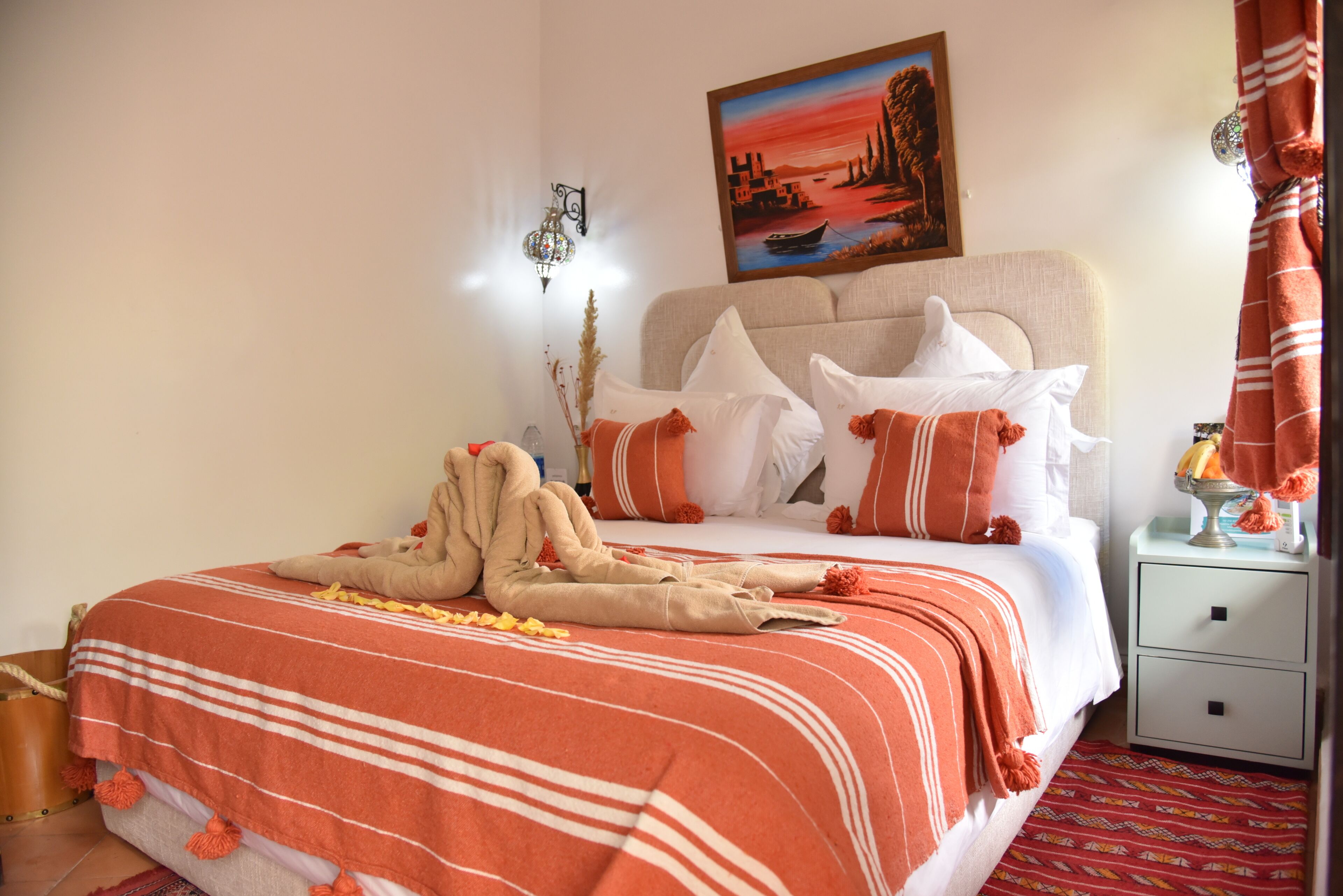 Una cama bien hecha con una manta a rayas, cabecera y almohadones decorativos.