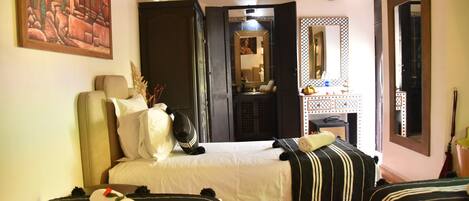 A hotel room with a bed, two bedside tables, a mirror, and a painting on the wall.
