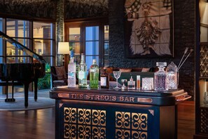 A bar area with a piano, various bottles, and a decorative wall.