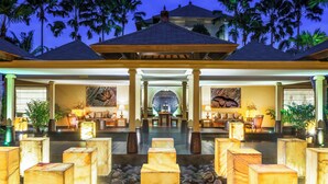 Een resort met een centrale lobby, palmbomen en een zwembad.