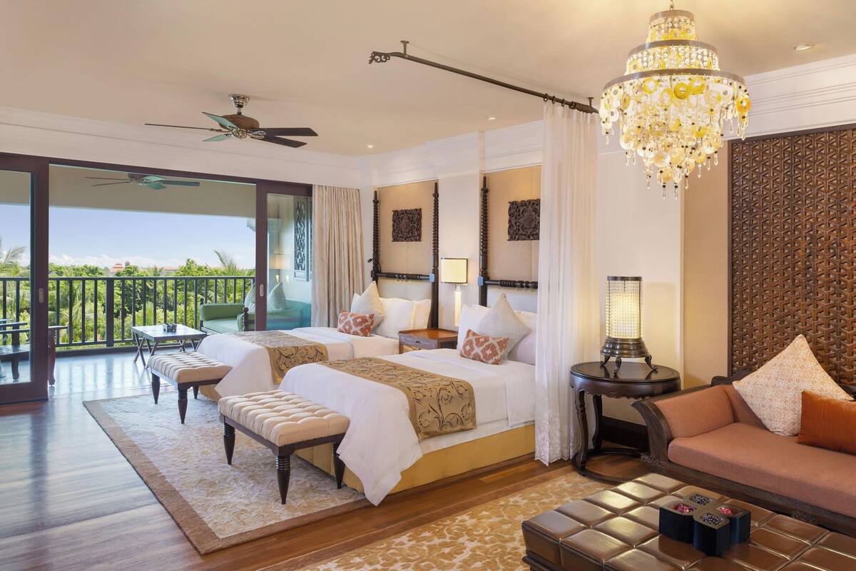 Une chambre spacieuse avec deux lits, un balcon et un lustre.