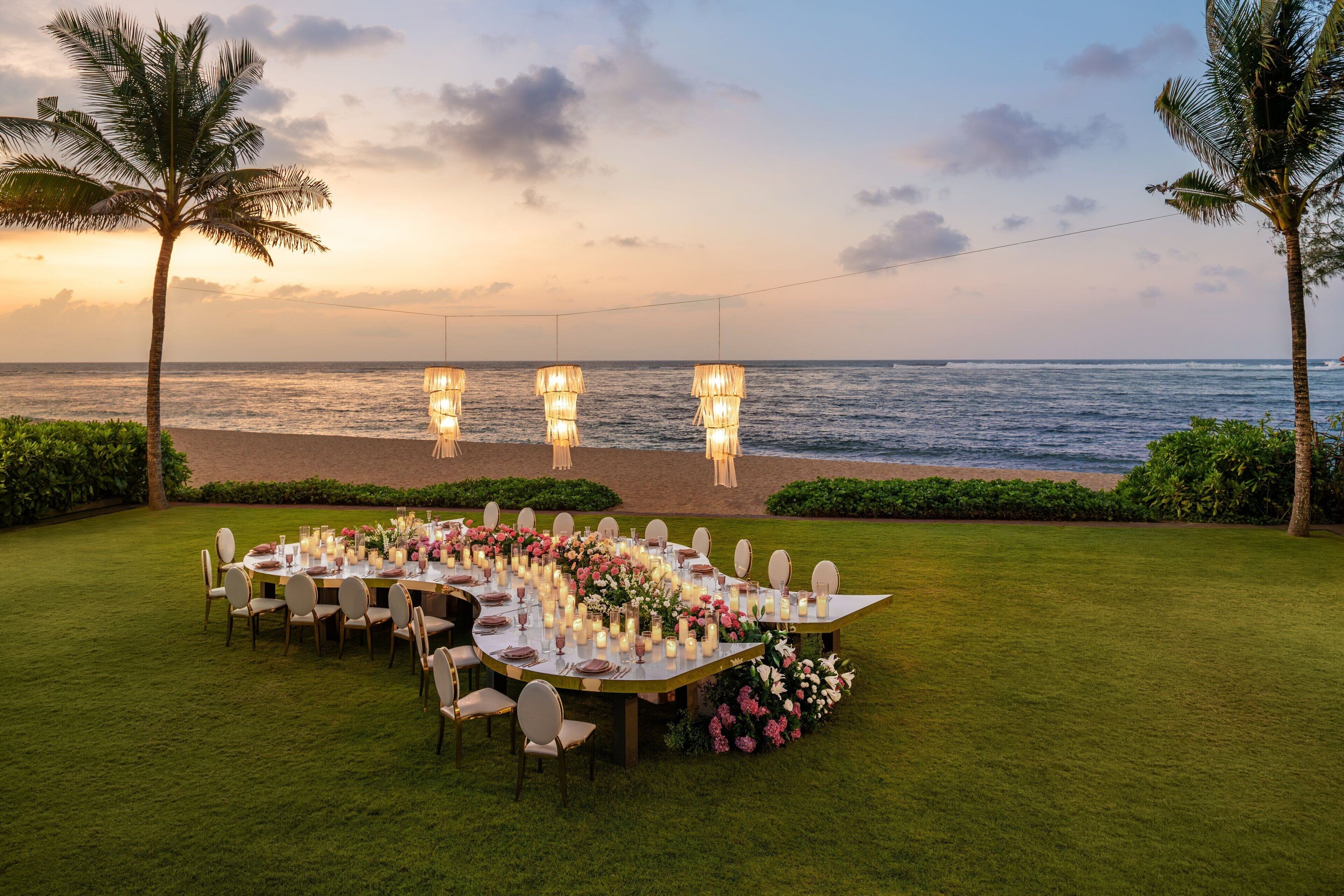 An outdoor dining setup with a view of the ocean at sunset.