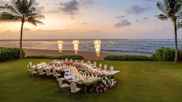 An outdoor dining setup with a view of the ocean at sunset.