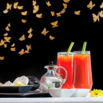 A table with towels, a bowl of snacks, a pitcher, and two glasses of red drink.