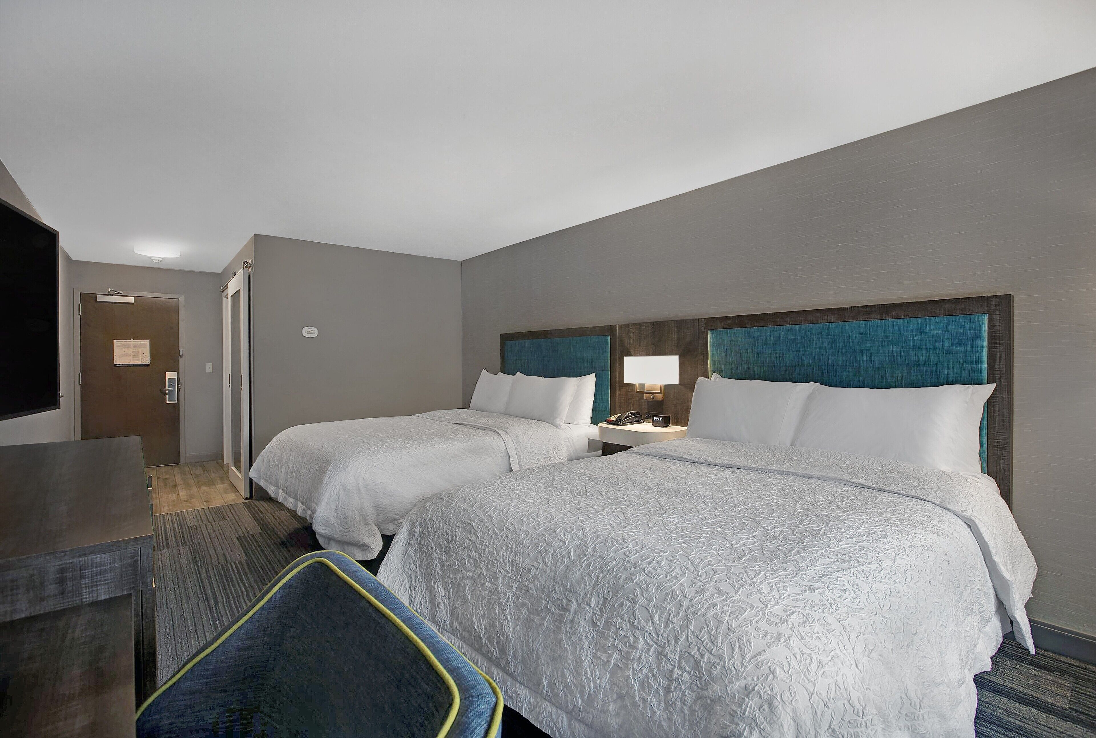 Ein Hotelzimmer mit zwei Betten, einem Schreibtisch und einem Fernseher.