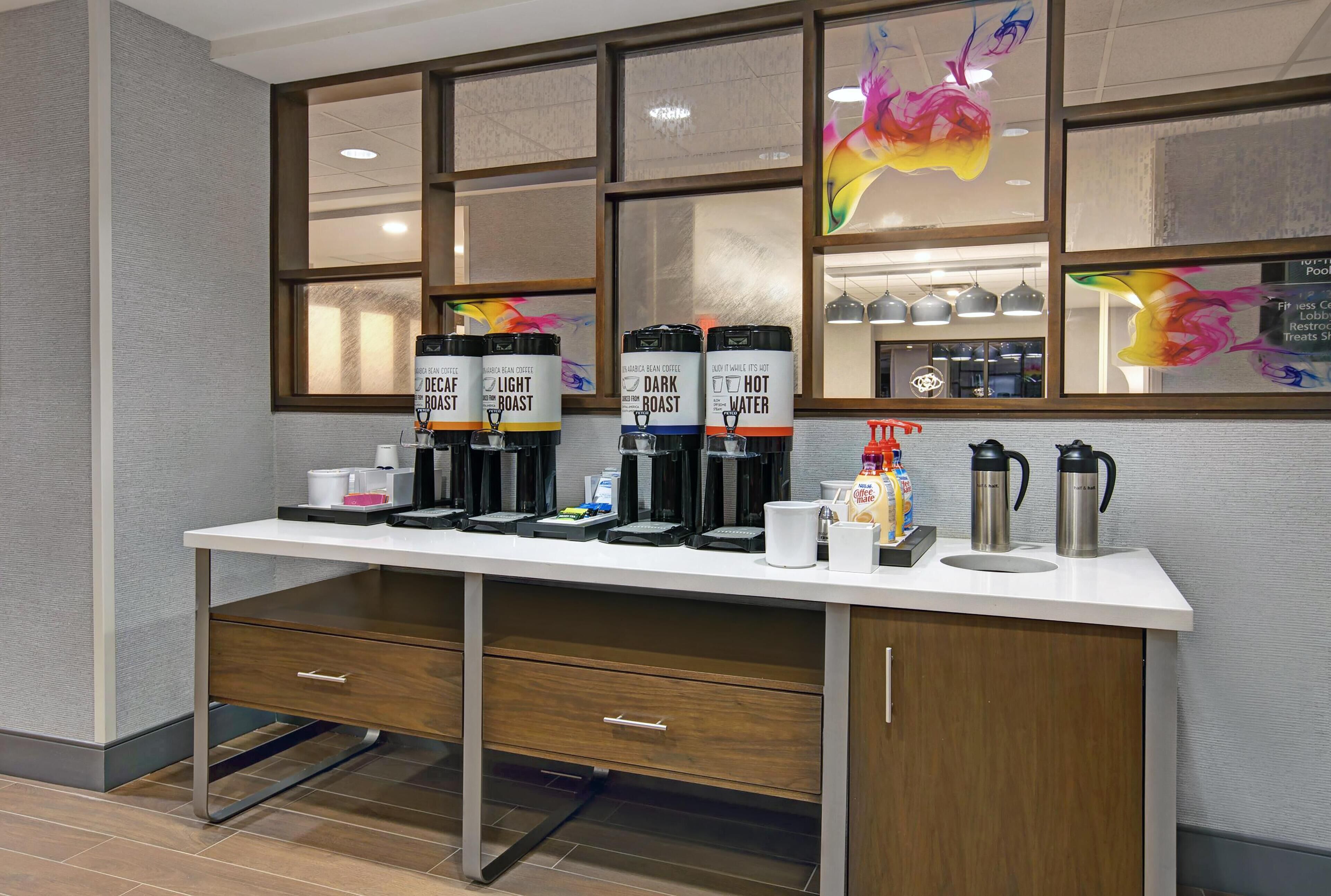 Una estación de café con varias cafeteras y un dispensador de agua.