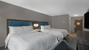 Ein Hotelzimmer mit zwei Betten, einem Schreibtisch, einem Stuhl und einem Fernseher.