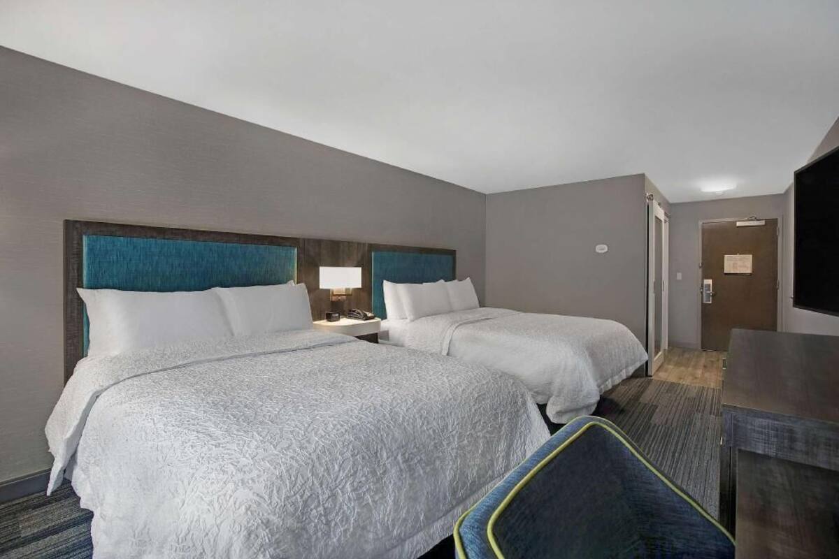A hotel room with two beds, a desk, and a television.
