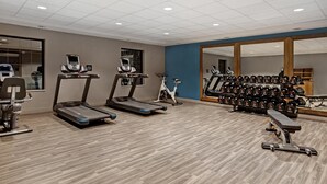 A gym with treadmills, an elliptical, a stationary bike, and a bench press.