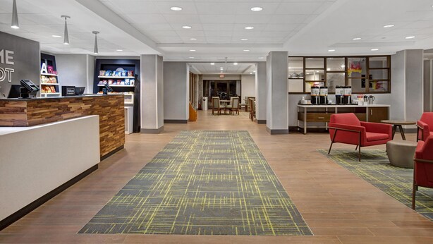 A hotel lobby with a reception desk, seating area, and a dining section.