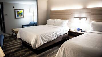 A hotel room with a large bed, a bedside table, a chair, and a desk.
