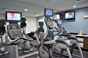 Une salle de sport équipée de tapis de course, chacun doté d’un écran numérique et d’un panneau de commande.