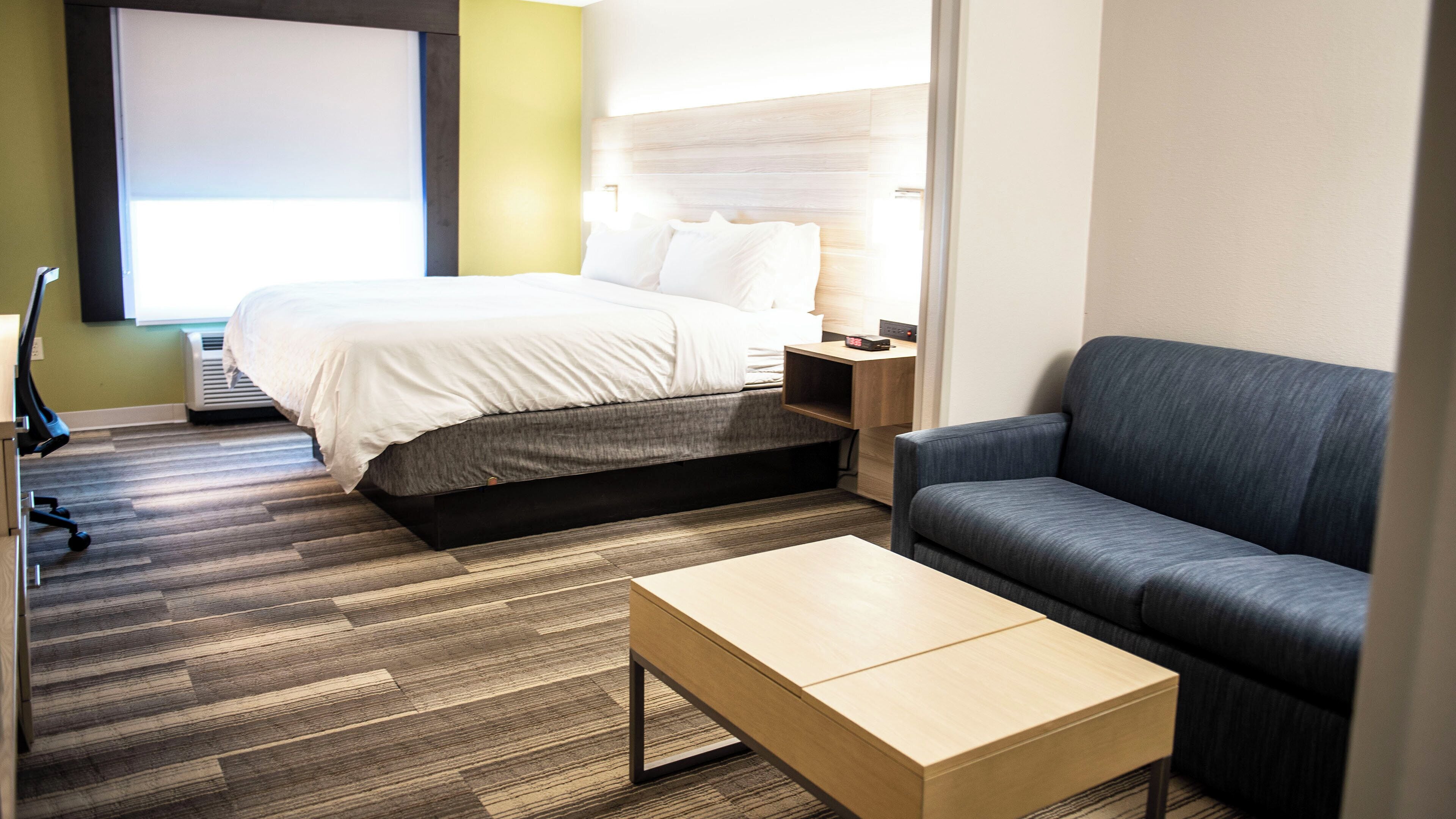 Une chambre d’hôtel avec un lit, un canapé, une table basse et un bureau avec une lampe.