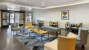 Een moderne hotellobby met een zithoek, een receptiebalie en een ingelijst kunstwerk aan de muur.