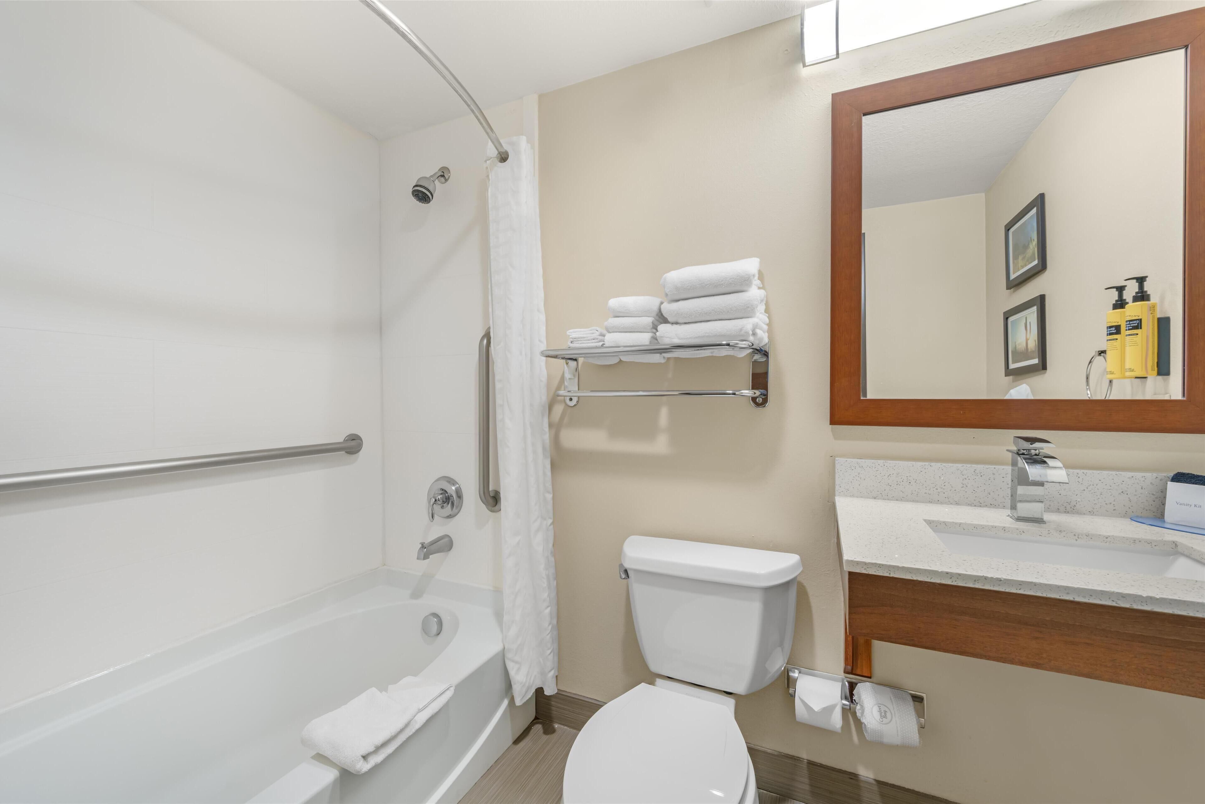 A bathroom with a bathtub, toilet, and sink. There is a shower curtain, a towel rack, and a mirror.