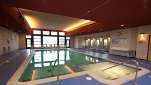 An indoor swimming pool with clear water, surrounded by lounge chairs and a blue floor. - Kewadin Casinos St. Ignace Hotel (St Ignace)
