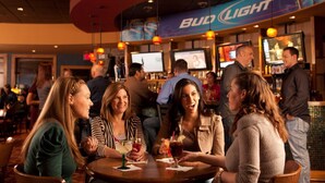 A group of people sitting at a bar with Bud Light branding. - Kewadin Casinos St. Ignace Hotel (St Ignace)