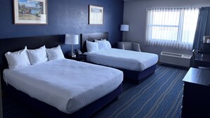 A hotel room with two beds, a desk, a chair, a lamp, a phone, and a picture on the wall. - Kewadin Casinos St. Ignace Hotel (St Ignace)