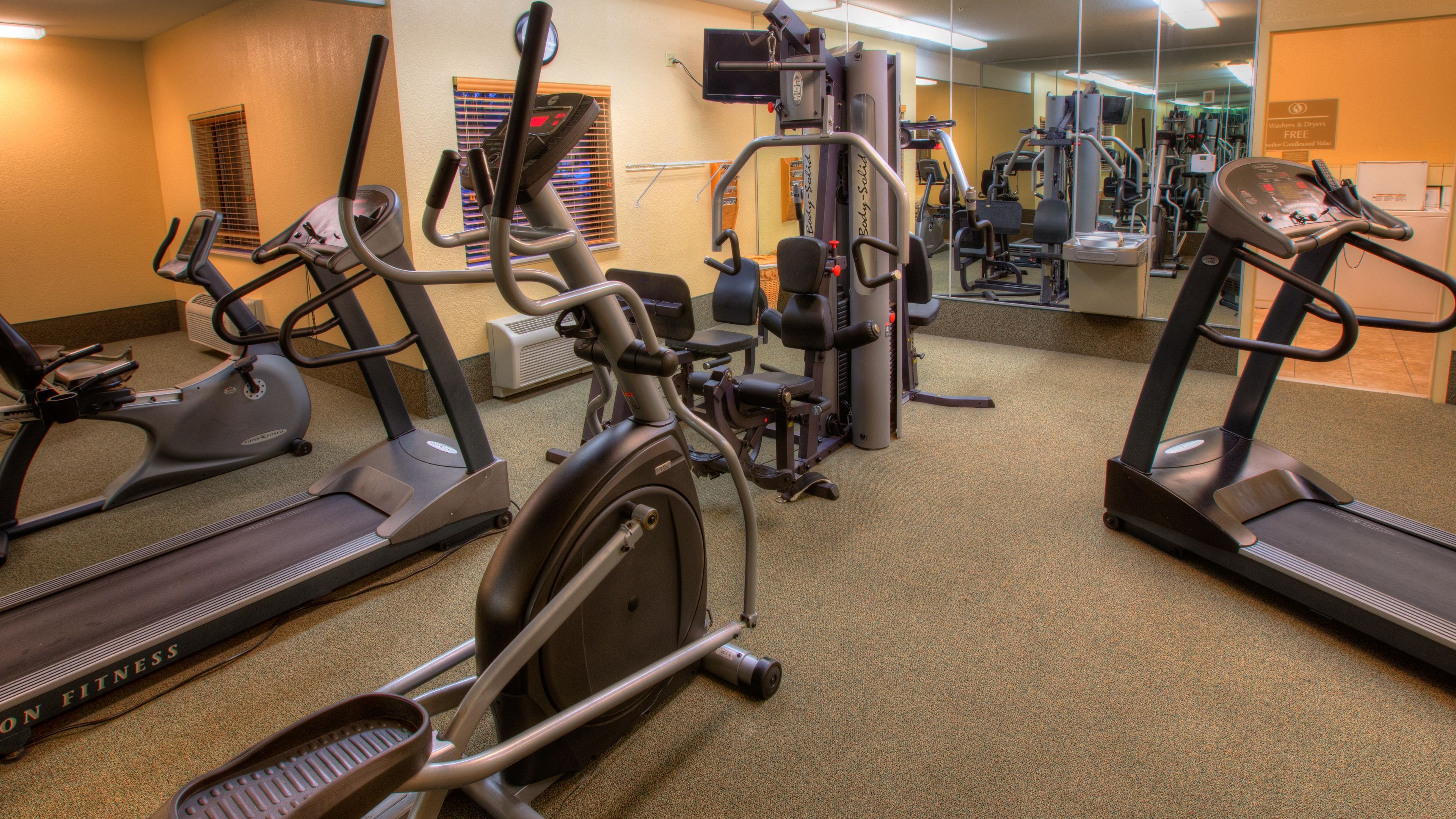 Un gimnasio con cintas de correr, elípticas y equipo de pesas.