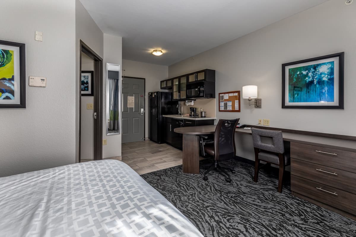 Une chambre d’hôtel comprenant un lit, un bureau, une chaise, un coin cuisine et une salle de bain.