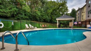 Piscina com espreguiçadeiras e um gazebo.