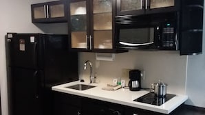 A compact kitchen with a black refrigerator, a microwave, and a stove. - Candlewood Suites Knoxville Airport-Alcoa by IHG (Alcoa)
