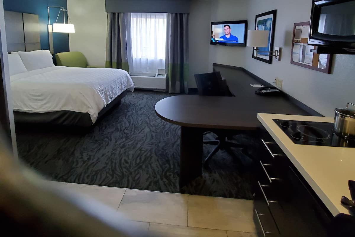 Une chambre d’hôtel équipée d’un lit, d’un bureau, d’une télévision et d’une kitchenette.