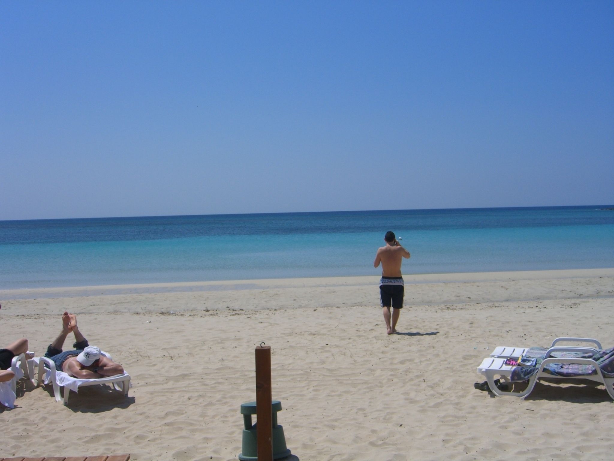 Una playa con tumbonas y una persona caminando.