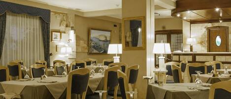 A hotel dining room with multiple tables and chairs, each set with tableware and a number on the table.