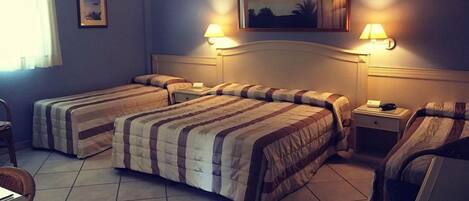 A hotel room with two single beds, a nightstand, a chair, and two wall-mounted lamps.
