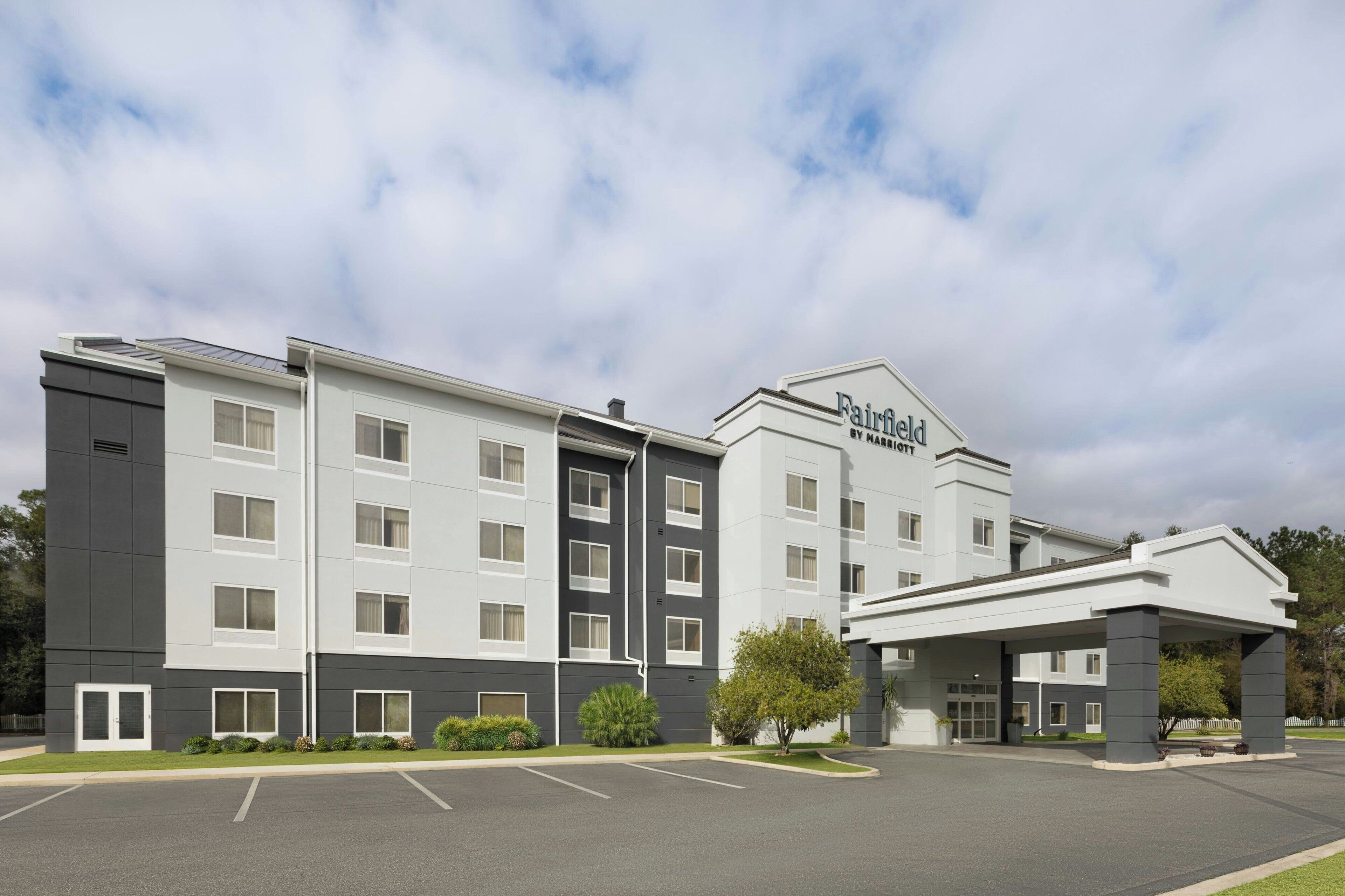 A Fairfield hotel with a modern design, featuring a parking lot and a covered entrance.