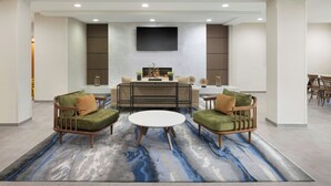 A modern living room with two green sofas, a white coffee table, and a flat-screen TV mounted on the wall. - Fairfield Inn & Suites Lake City (Lake City)