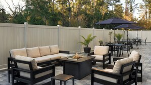 An outdoor patio area with a sectional sofa, chairs, a coffee table, and a fire pit. - Fairfield Inn & Suites Lake City (Lake City)