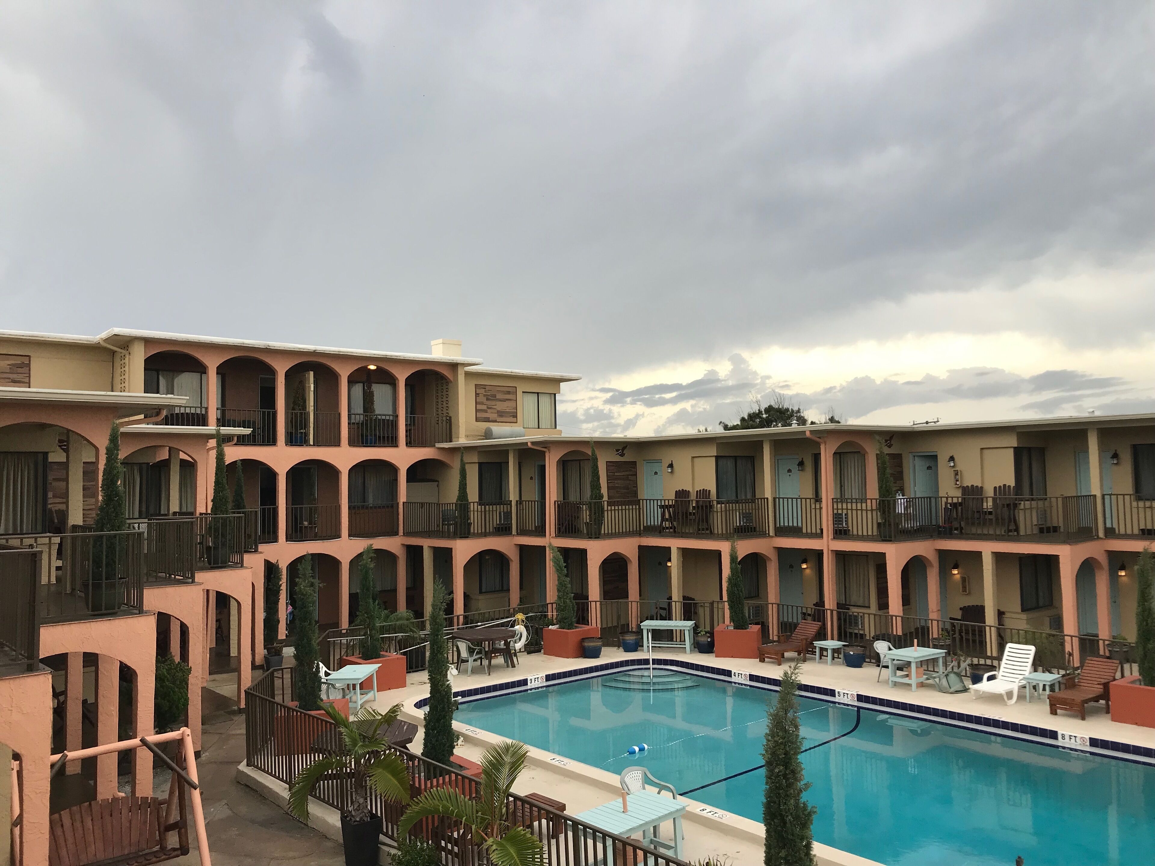 A hotel with a pool area, multiple balconies, and outdoor seating.