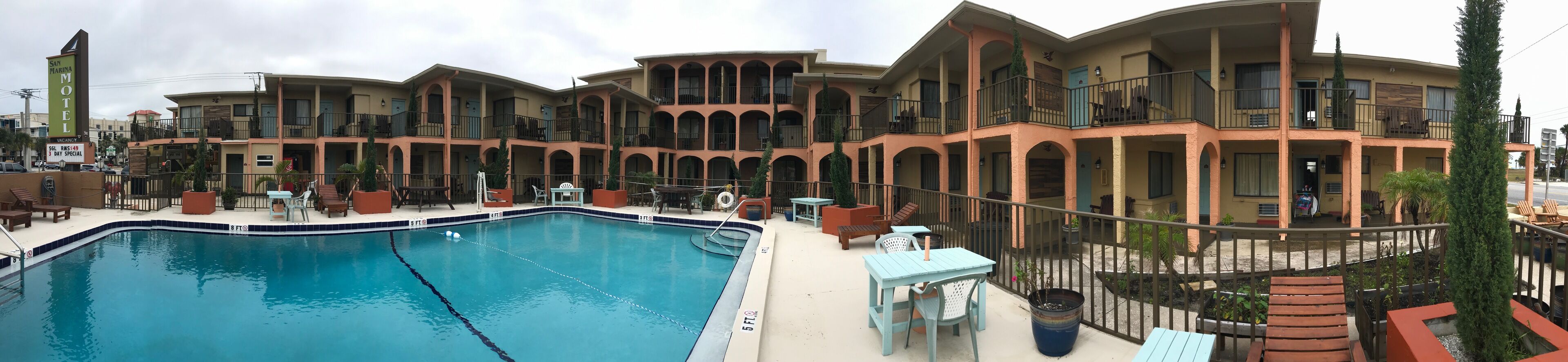 A multi-story motel with a swimming pool, outdoor seating, and a large sign advertising a 3-day special.