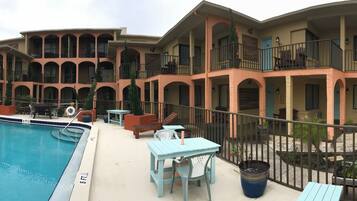 A multi-story motel with a swimming pool, outdoor seating, and a large sign advertising a 3-day special.
