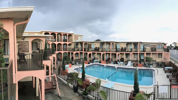 A hotel with a pool area, outdoor seating, and a multi-story building with balconies. - San Marina Motel (Daytona Beach)