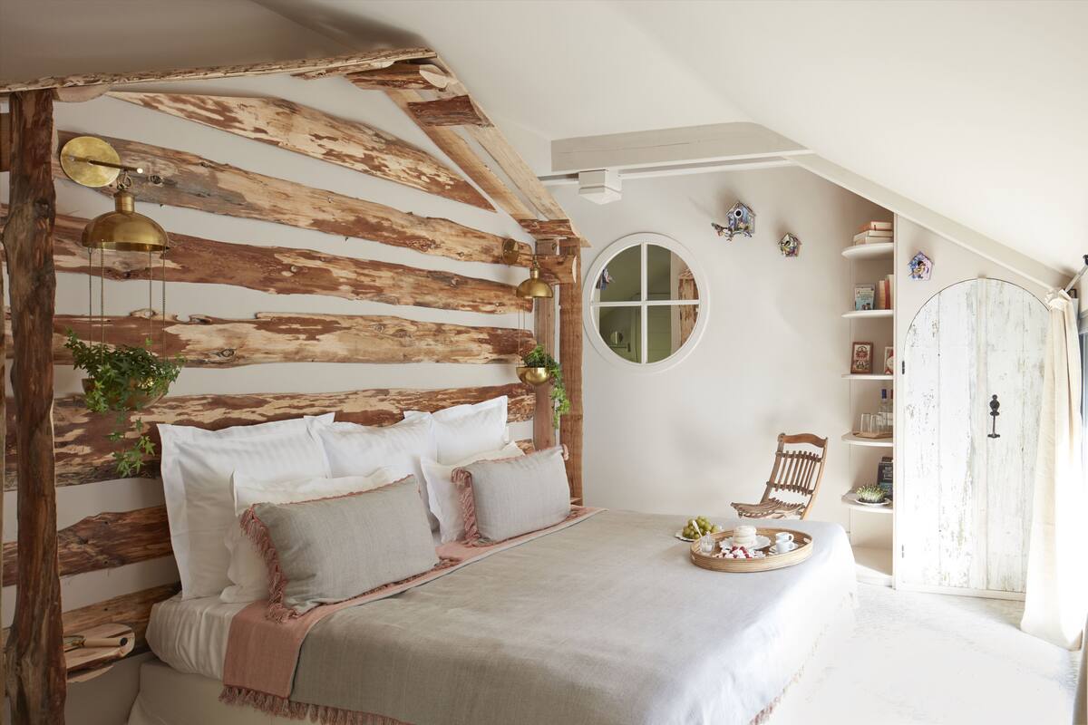 Un dormitorio con cabecera de madera, un espejo redondo, una mesita de noche con bandeja y un armario.