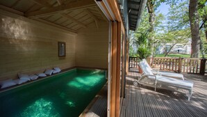 Una terraza de madera con piscina, sillas de descanso y techo de madera.