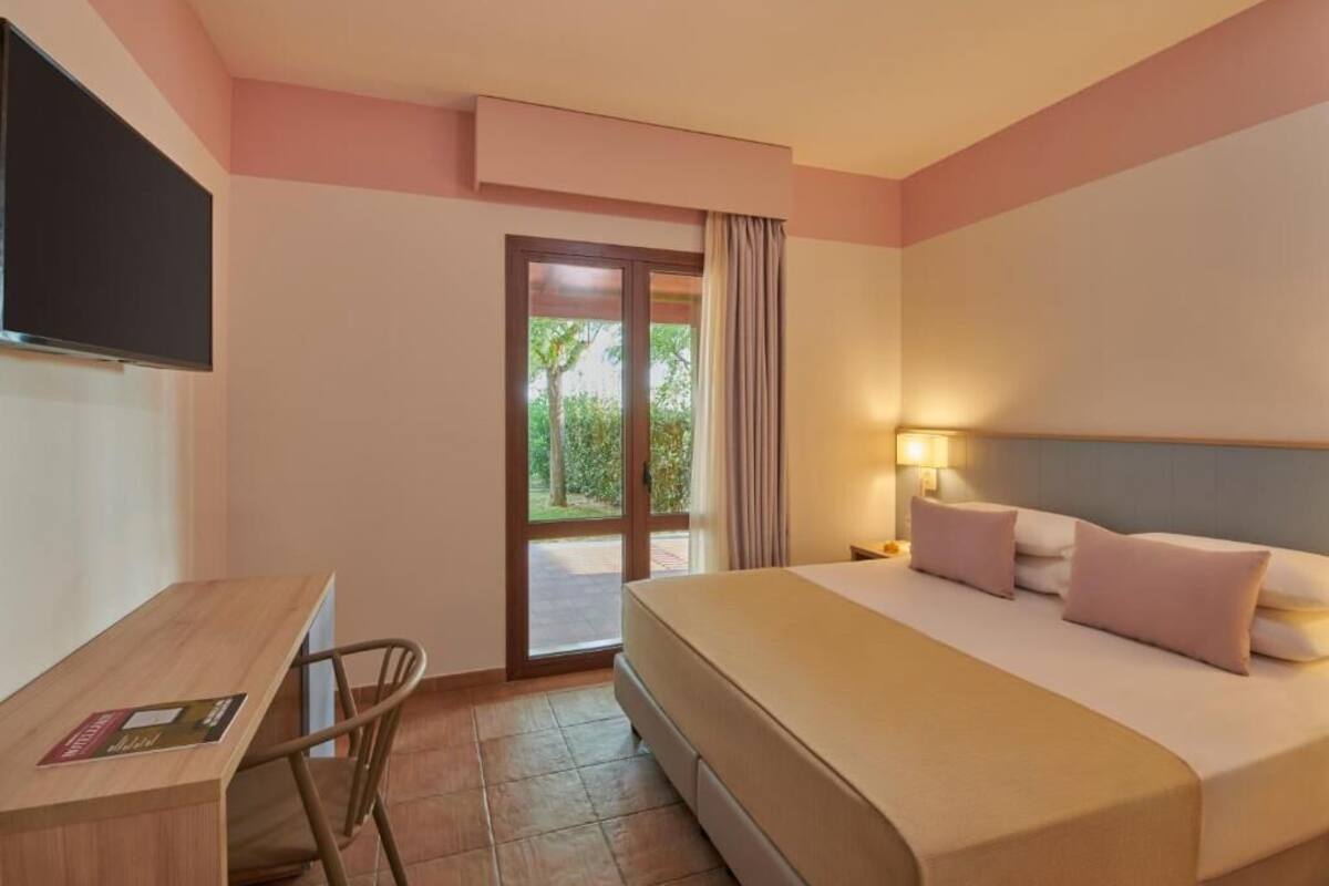 A hotel room with a bed, a desk, and a television.
