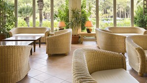 A covered outdoor seating area with wicker furniture and a view of the garden.