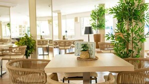 A dining area with a table, wicker chairs, and potted plants. - Hotel THB Dos Playas - Adults Only (Capdepera)