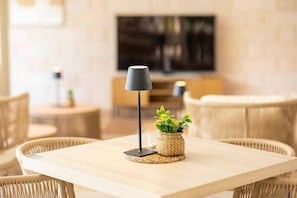 Ein modernes Wohnzimmer mit einem Holztisch, Korbstühlen, einer Stehlampe und einem kleinen Topfpflanzen.