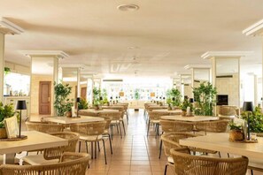 A spacious dining area with multiple tables and chairs, surrounded by mirrors and plants. - Hotel THB Dos Playas - Adults Only (Capdepera)