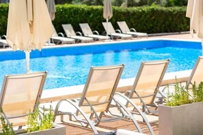 A swimming pool with lounge chairs and umbrellas. - Hotel THB Dos Playas - Adults Only (Capdepera)