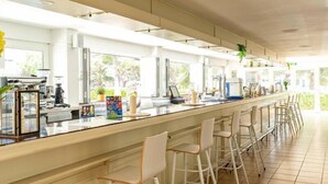 A long bar area with stools, a counter with coffee machines, and large windows. - Hotel THB Dos Playas - Adults Only (Capdepera)