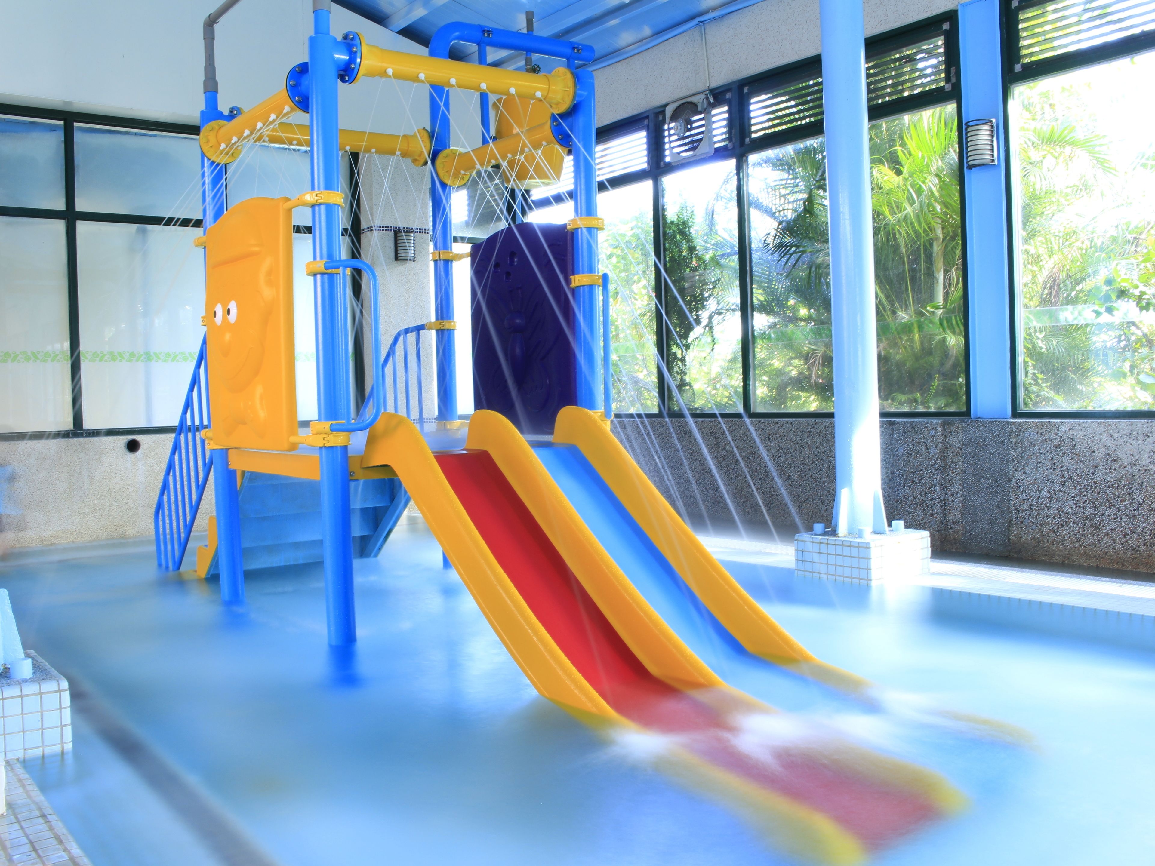 Ein überdachter Wasserpark mit Rutschen und Kletterelementen.