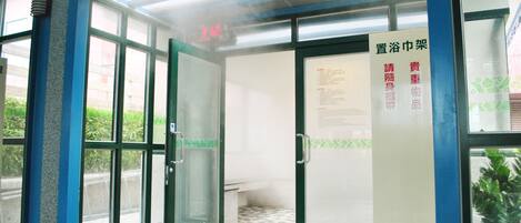 Entrada de un edificio con puertas de vidrio, piso de baldosas y un letrero con texto.